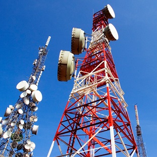 three telecommunications towers highlighted against a blue sky