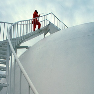 worker climbing steps to top of liquid gas storage tank at natural gas plant