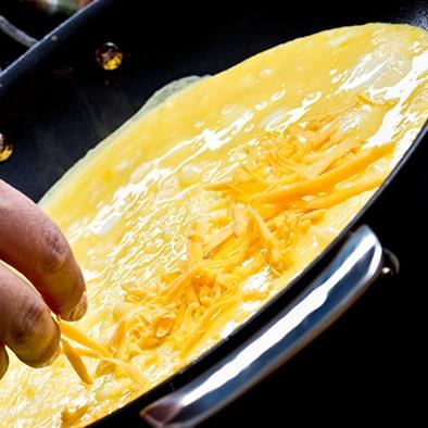 person making a cheese omlet in a frying pan