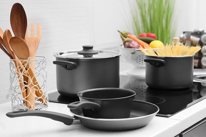 two pots on a flat top electric stove saucepan and frying pan on counter