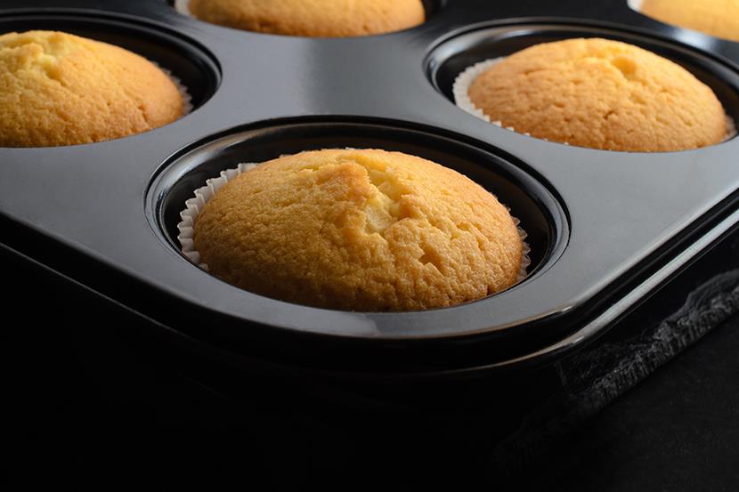 baked cupcakes in black muffin tin cooling on a slate
