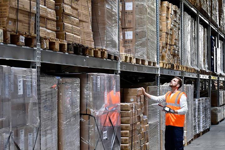 man in warehouse wearing orange safety vest looking up