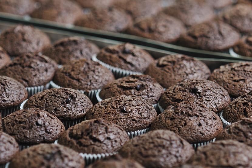 large quantity of cupcakes or muffins on commercial baking sheet