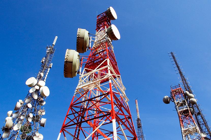 three telecommunications towers highlighted against a blue sky