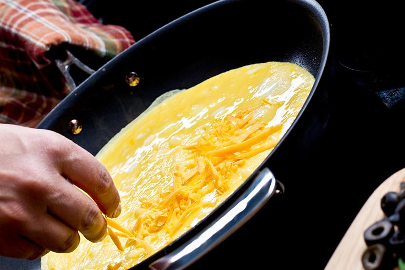 person making a cheese omlet in a frying pan