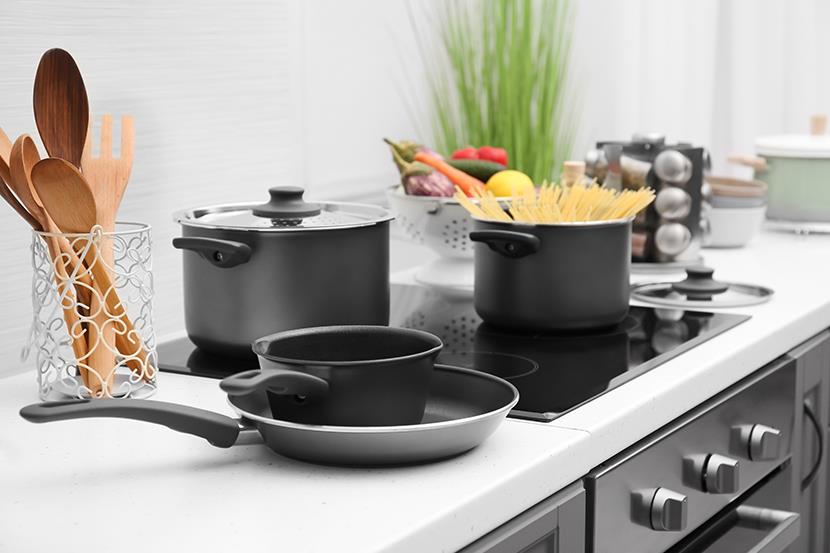 two pots on a flat top electric stove saucepan and frying pan on counter