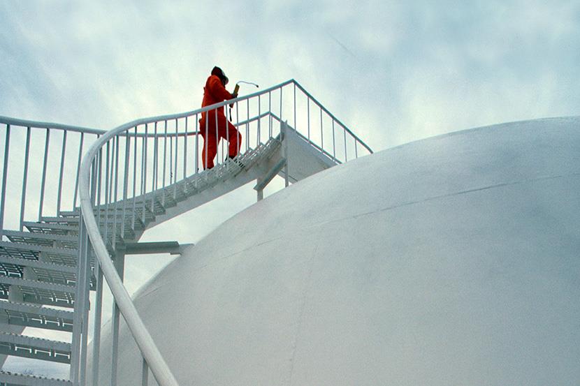 worker climbing steps to top of liquid gas storage tank at natural gas plants