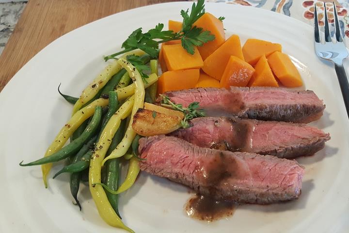 Slices of steakhouse steak on a dinner plate.