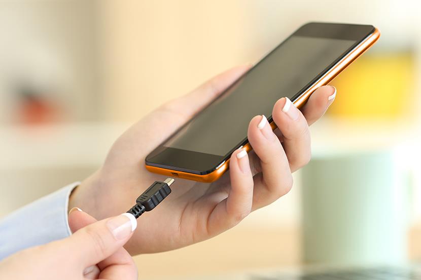womans hands holding smartphone and charger